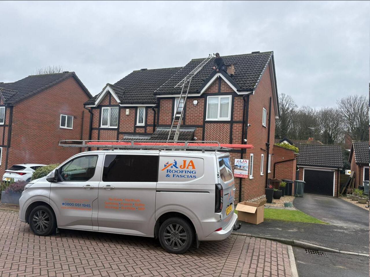 JA Roofing van on a driveway with a roofer carrying out repairs on a pitched roof